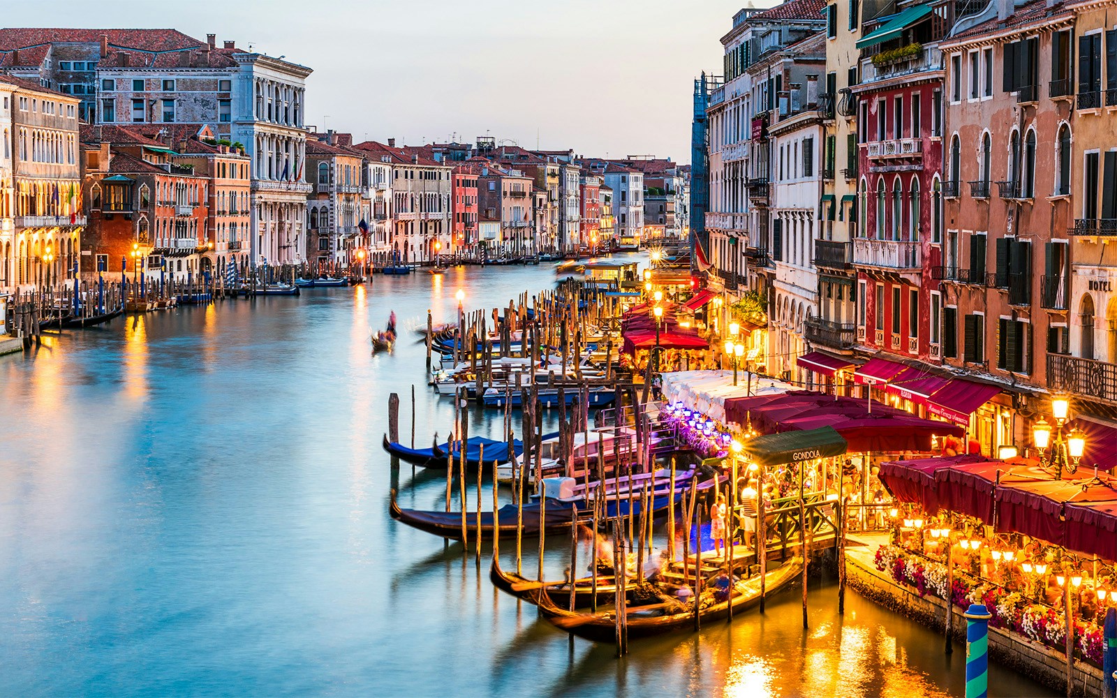 Venice Grand Canal with gondolas and illuminated waterfront at dusk.
