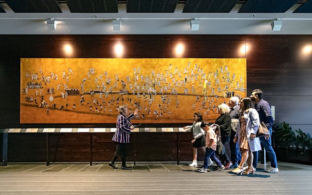 Tour group viewing artwork at Melbourne Cricket Ground (MCG) during guided tour.