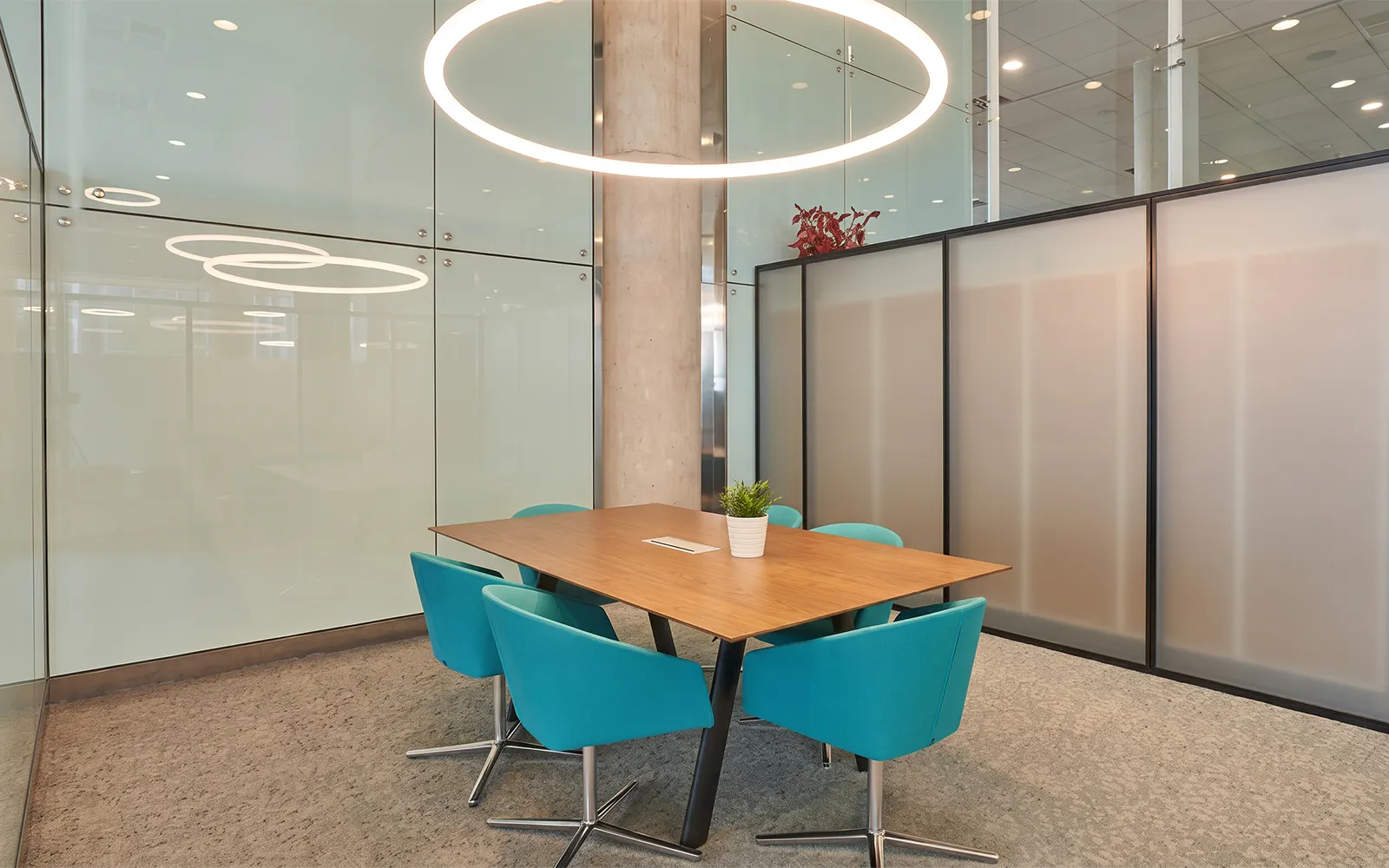 Meeting area with turquoise chairs and wooden table in Colomer VIP Lounge, Barcelona El Prat Airport (T1).