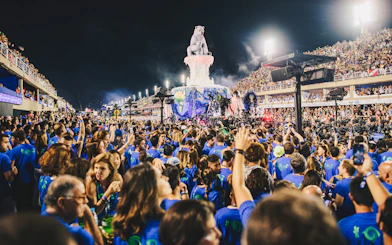 Crowd enjoying Rio Carnival parade at Marquês de Sapucaí, Rio de Janeiro, with vibrant floats and performers.