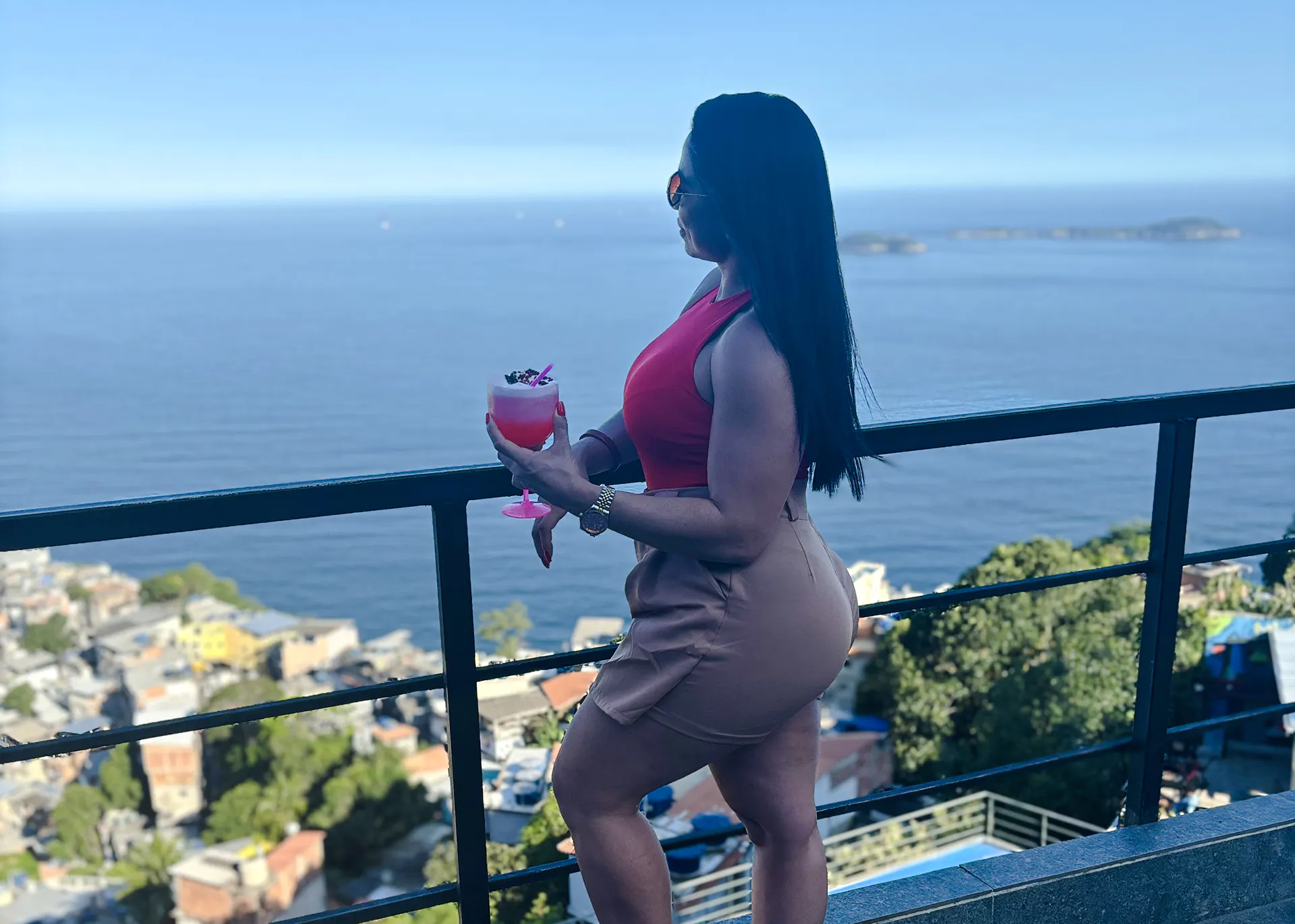Woman enjoying a drink with a view of Vidigal and the ocean in Rio de Janeiro.