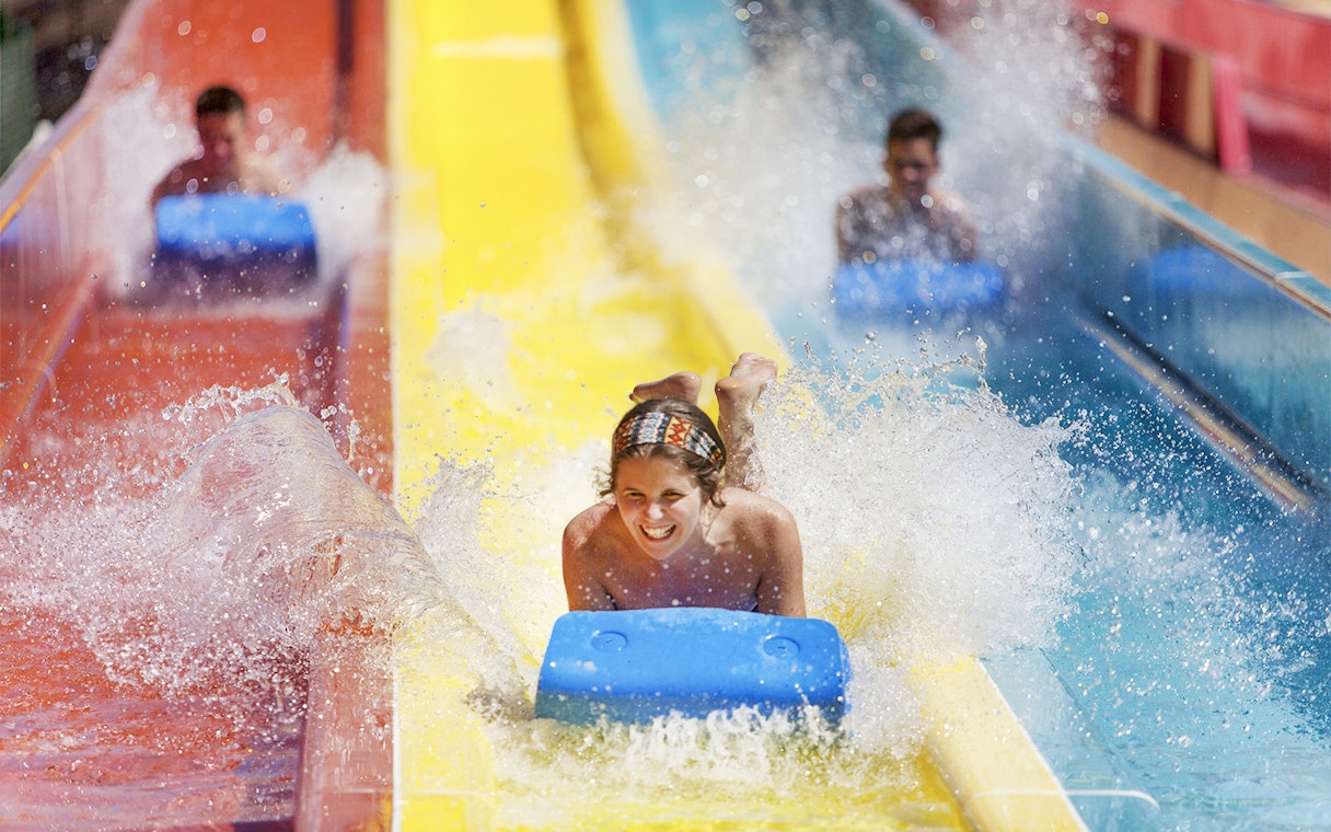 Person enjoying a water slide at Agua Mágica, part of Isla Mágica in Seville.