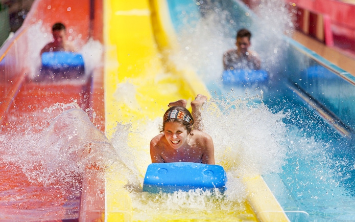 Person enjoying a water slide at Agua Mágica, part of Isla Mágica in Seville.