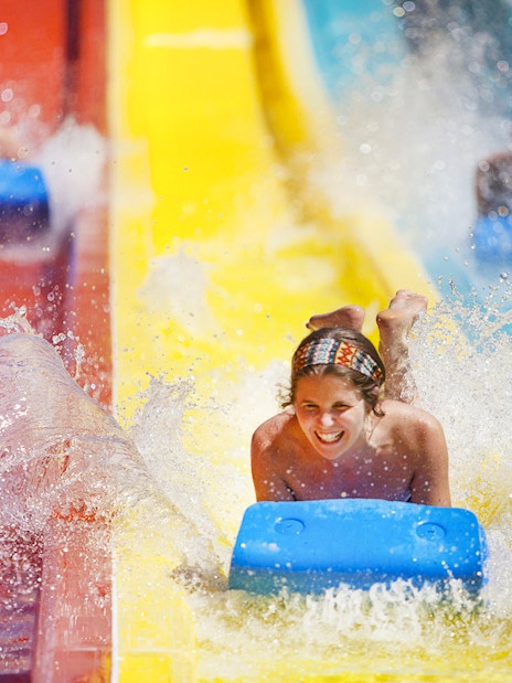 Person enjoying a water slide at Agua Mágica, part of Isla Mágica in Seville.