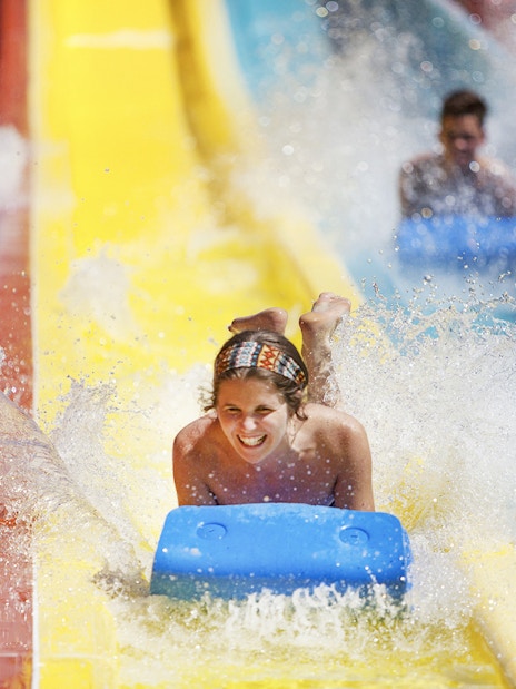 Person enjoying a water slide at Agua Mágica, part of Isla Mágica in Seville.