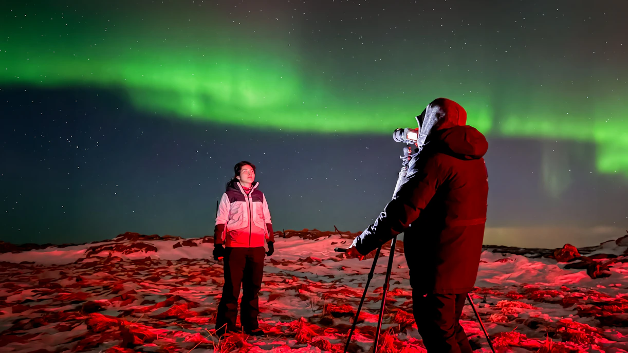 Guest posing under Northern Lights on Reykjavik 4x4 tour.