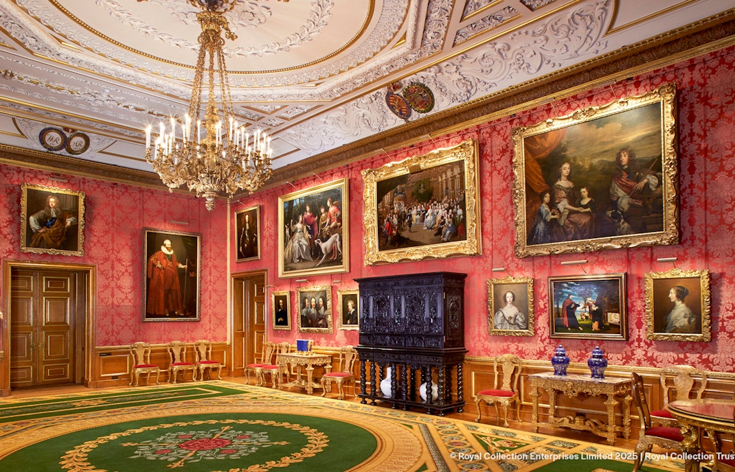 Windsor Castle interior with ornate ceiling, chandelier, and paintings on red walls.