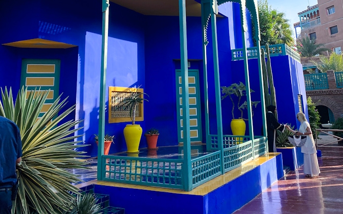 Jardin Majorelle's vibrant blue building with potted plants and visitors in Marrakech.