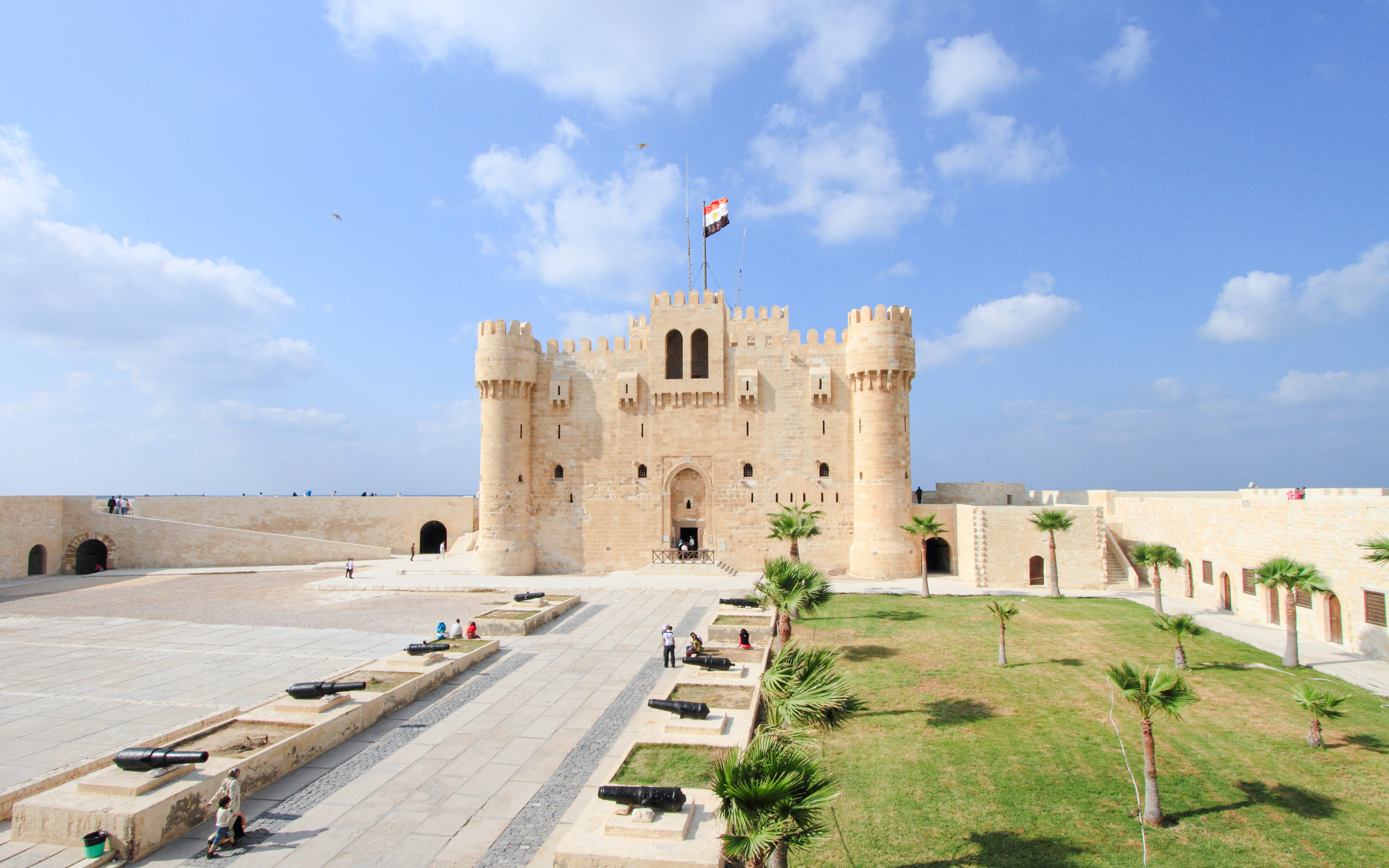 Panoramic view of Qaitbay Citadel in Alexandria with surrounding courtyard and cannons.