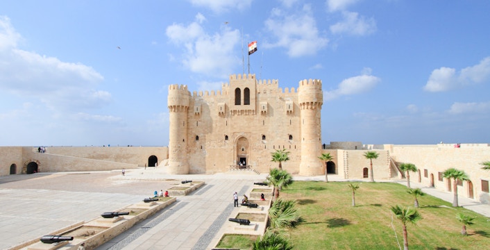 Panoramic view of Qaitbay Citadel in Alexandria with surrounding courtyard and cannons.