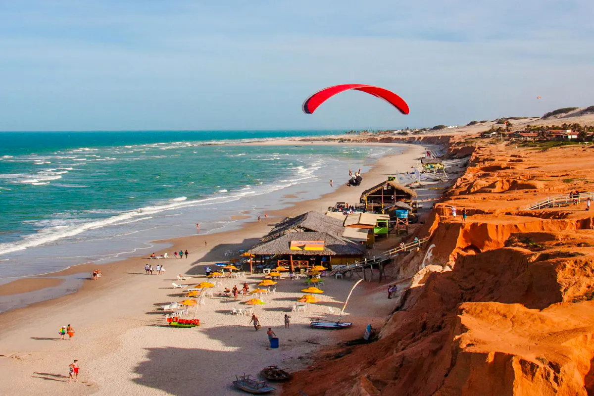 Paragliding over colorful cliffs and beach at Canoa Quebrada, Brazil.