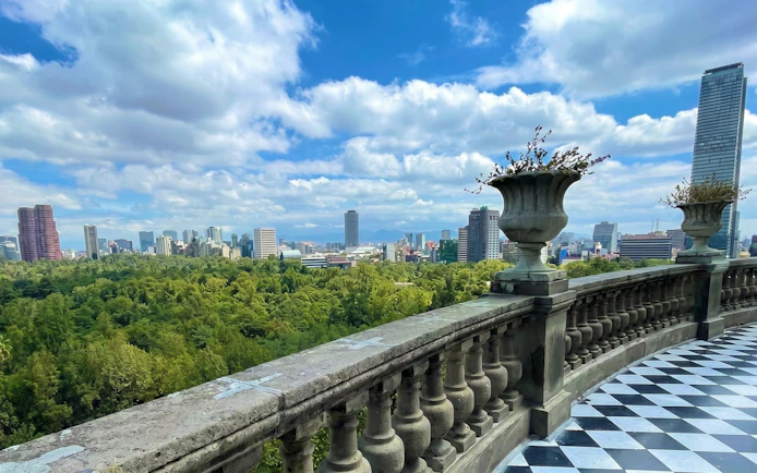 View from Chapultepec Castle balcony overlooking Mexico City skyline and forest.