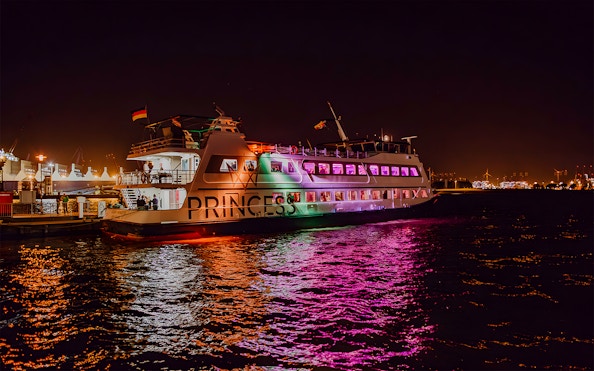 Large ship illuminated with colorful lights during evening cruise.