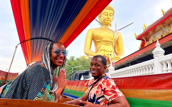 Longtail boat ride past a golden Buddha statue on Bangkok Canal Tour.