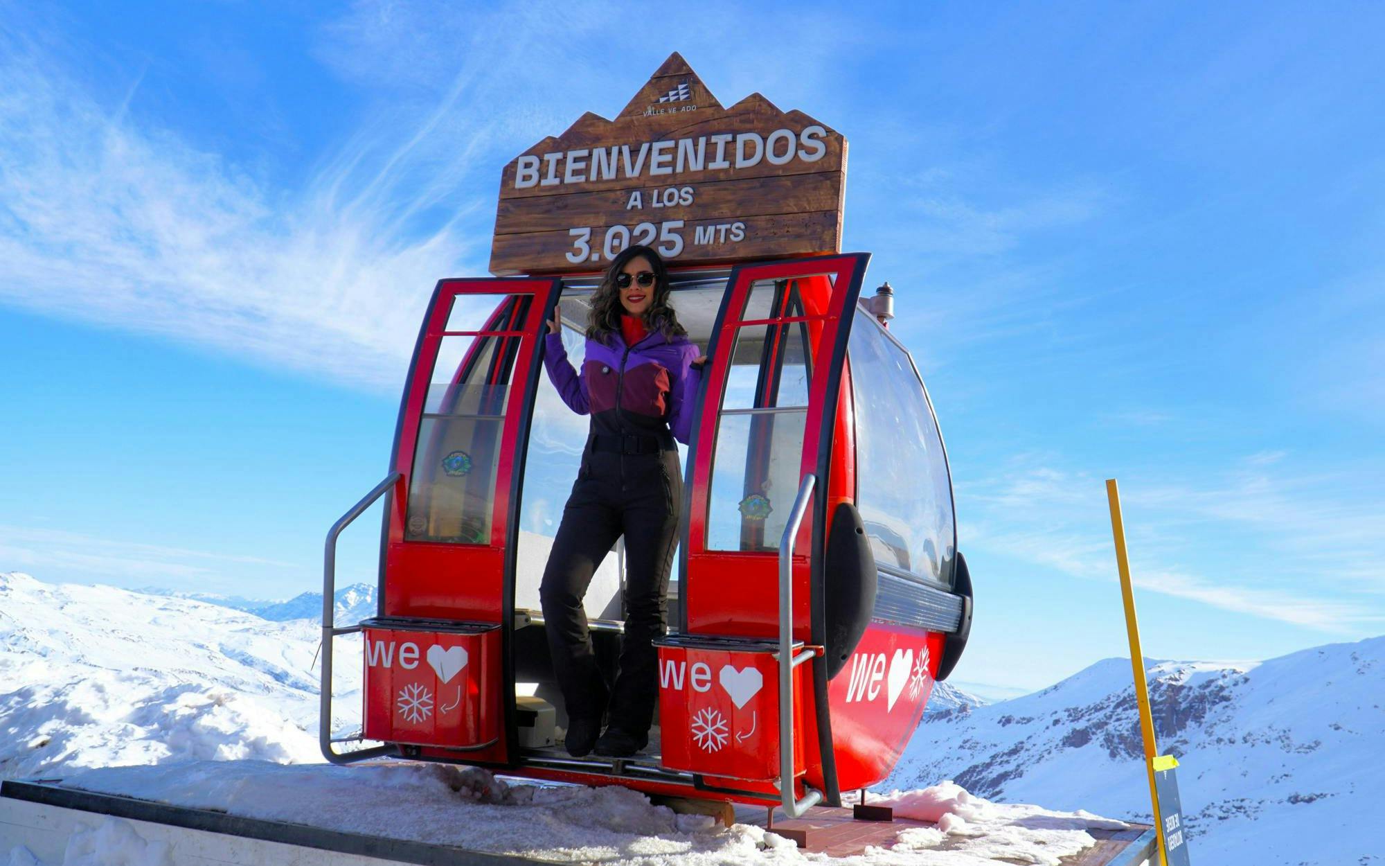 Tourist standing in a red gondola at Valle Nevado, Chile, with snowy mountains in the background.