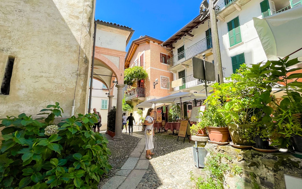 Cobblestone street with tourists and cafes in Isole Borromee, Italy.