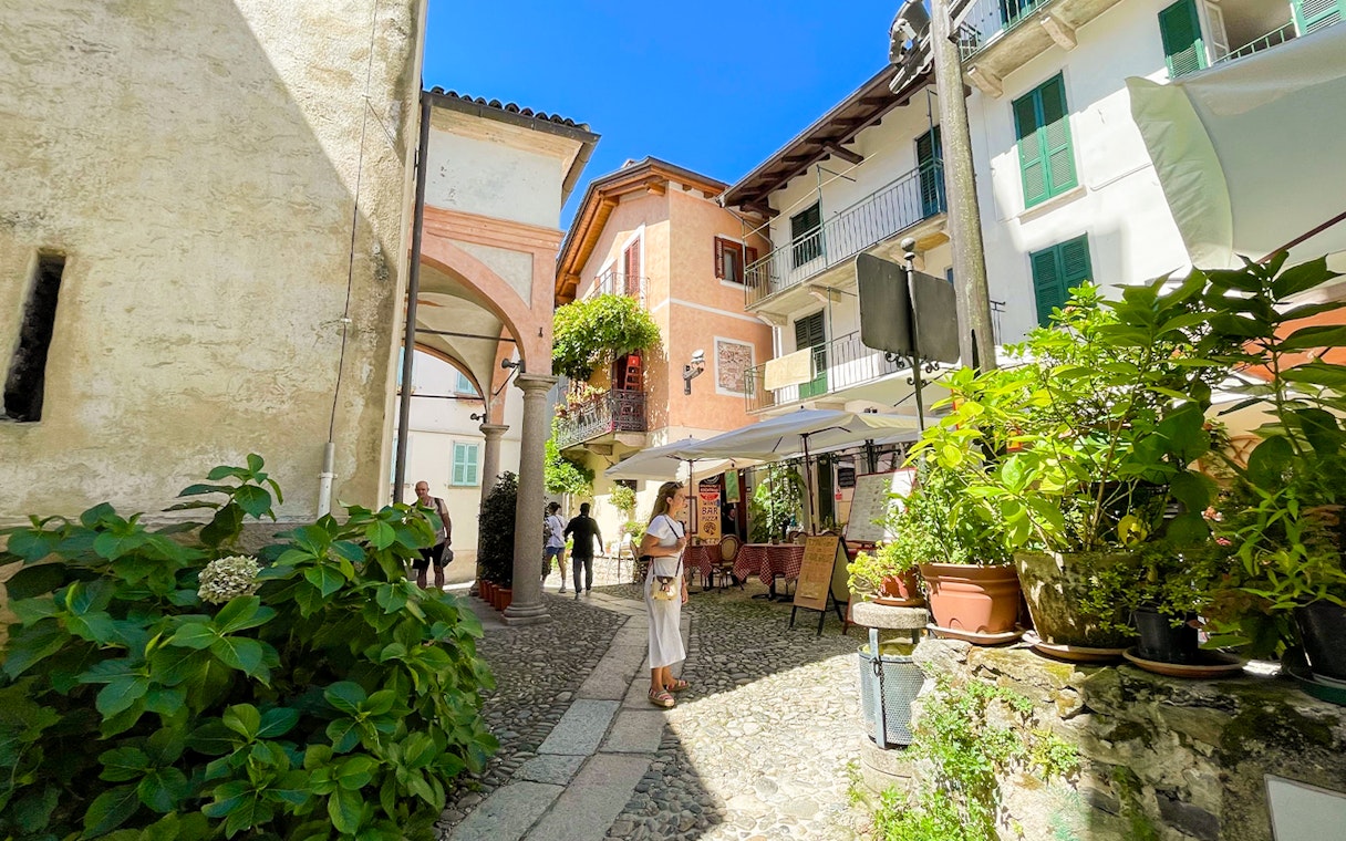 Cobblestone street with tourists and cafes in Isole Borromee, Italy.