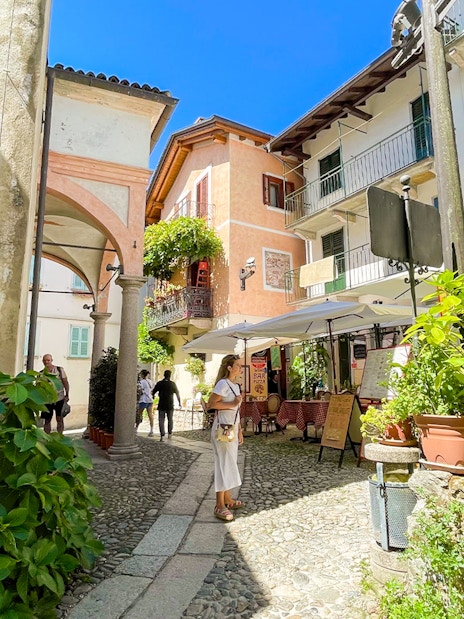 Cobblestone street with tourists and cafes in Isole Borromee, Italy.