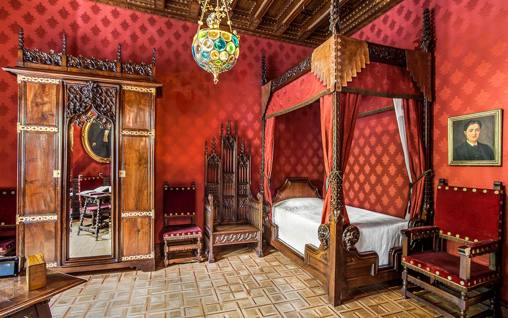 Casa Amatller bedroom with ornate wooden furniture and red decor, Barcelona.
