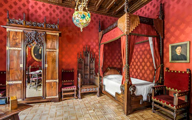 Casa Amatller bedroom with ornate wooden furniture and red decor, Barcelona.