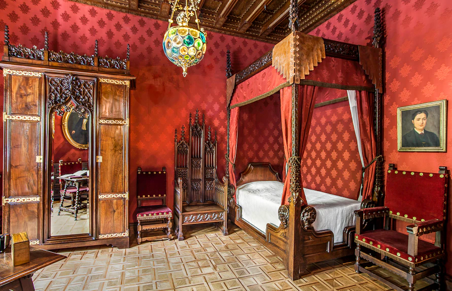 Casa Amatller bedroom with ornate wooden furniture and red decor, Barcelona.