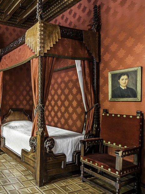 Casa Amatller bedroom with ornate wooden furniture and red decor, Barcelona.