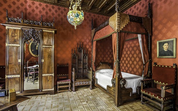 Casa Amatller bedroom with ornate wooden furniture and red decor, Barcelona.