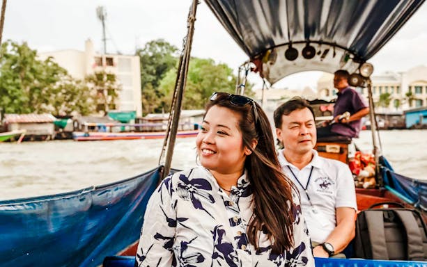 Tourists enjoying a ride on a long tail boat in a river setting.