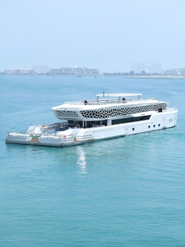 Lotus Mega Yacht sailing in Dubai Marina with cityscape in the background.
