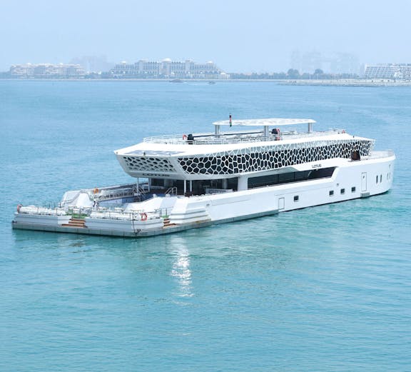 Lotus Mega Yacht sailing in Dubai Marina with cityscape in the background.
