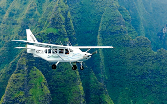 Small plane flying over lush green mountains in Kauai during air tour.