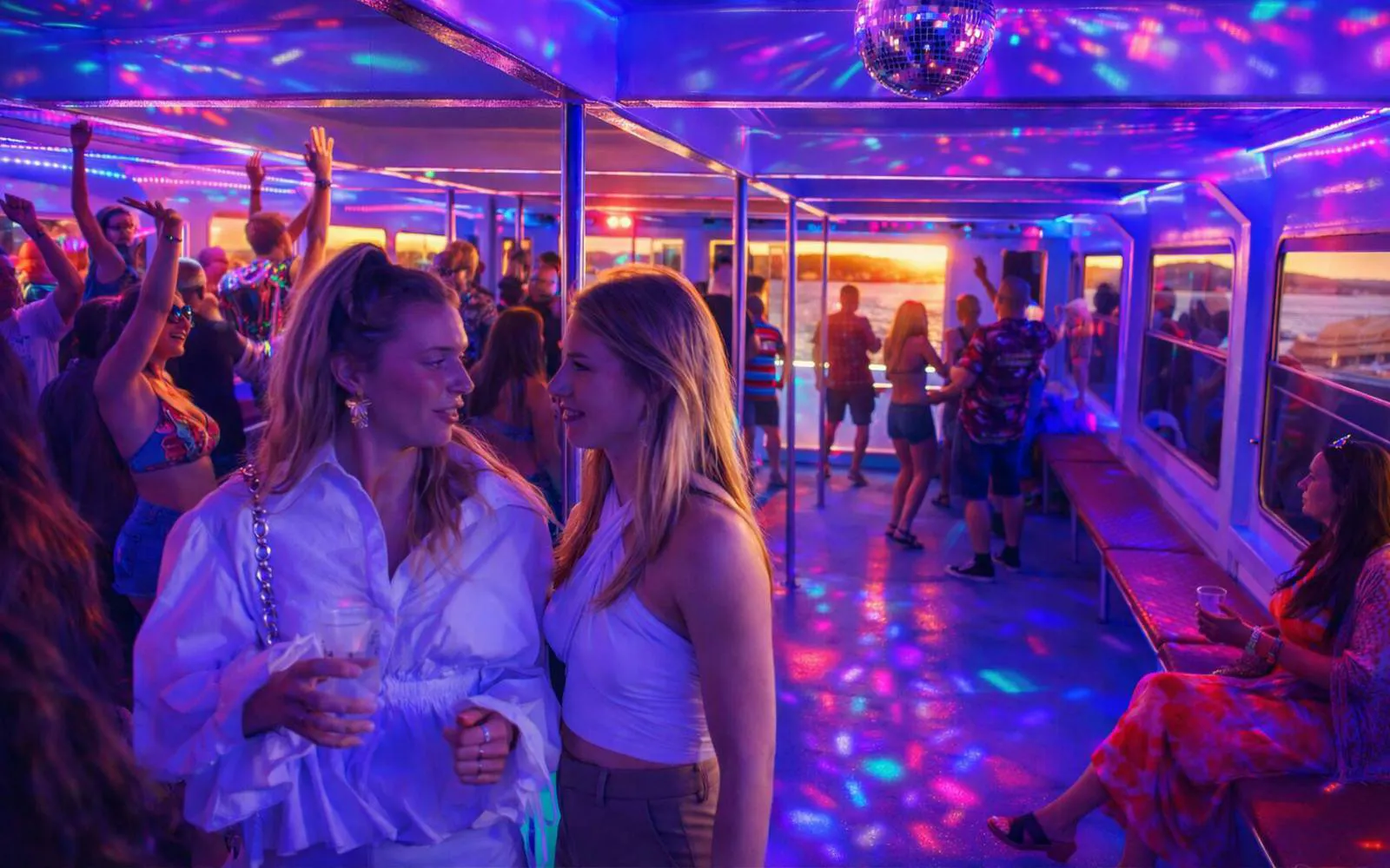 Lisbon boat party with DJ, colorful lights, and guests enjoying the sunset cruise.