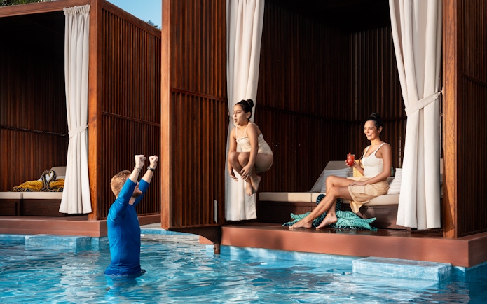 Girl jumping into pool as dad cheers at Grand Hyatt waterpark, Dubai.