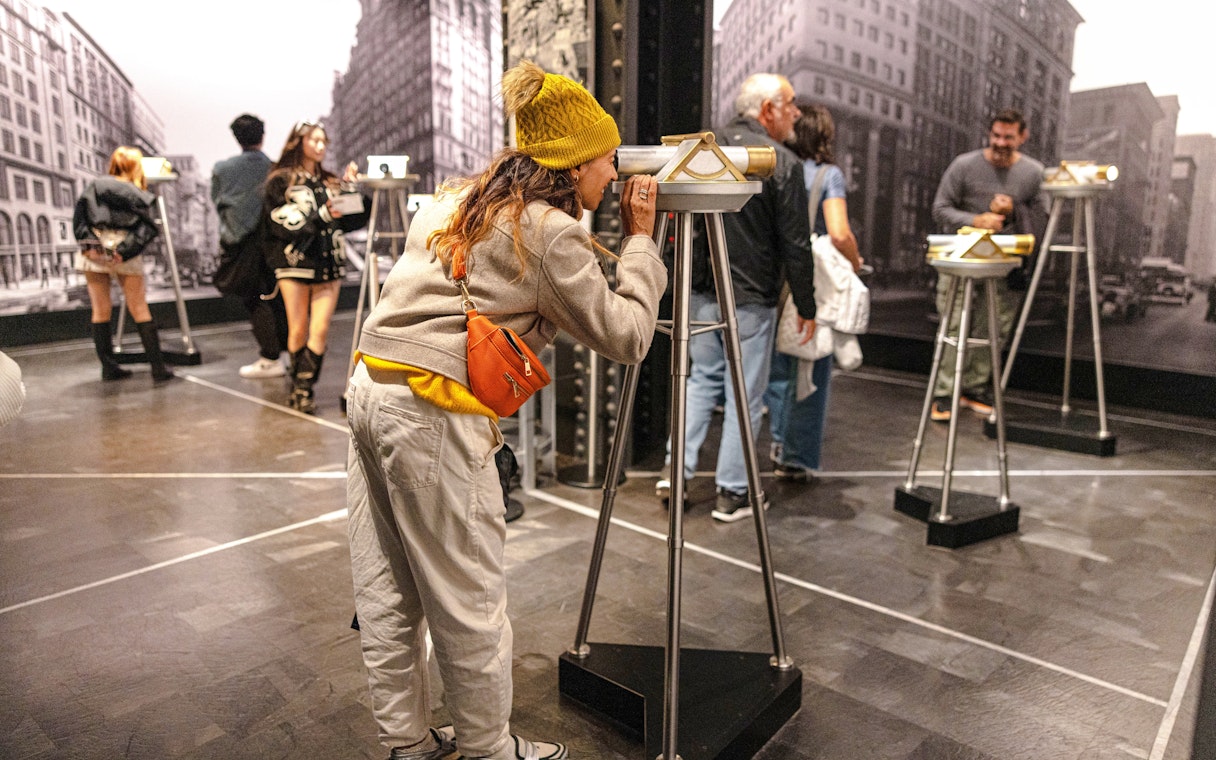 Guest using a viewing scope at Empire State Building exhibit.