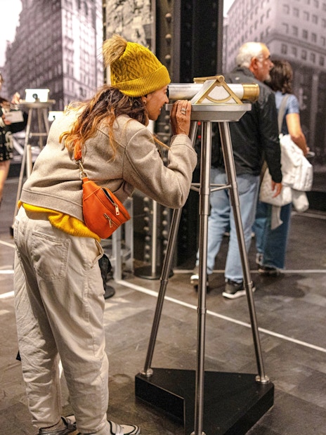 Guest using a viewing scope at Empire State Building exhibit.