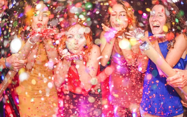 People celebrating with confetti at a New Year's Eve party.