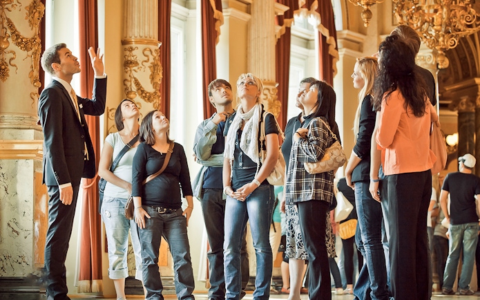 Tour group inside Semperoper Dresden with guide explaining architectural details.