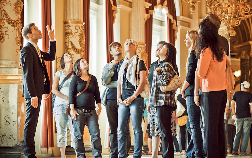 Tour group inside Semperoper Dresden with guide explaining architectural details.