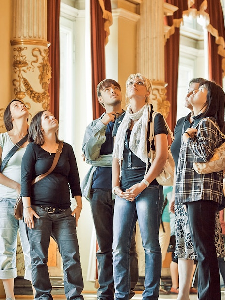 Tour group inside Semperoper Dresden with guide explaining architectural details.