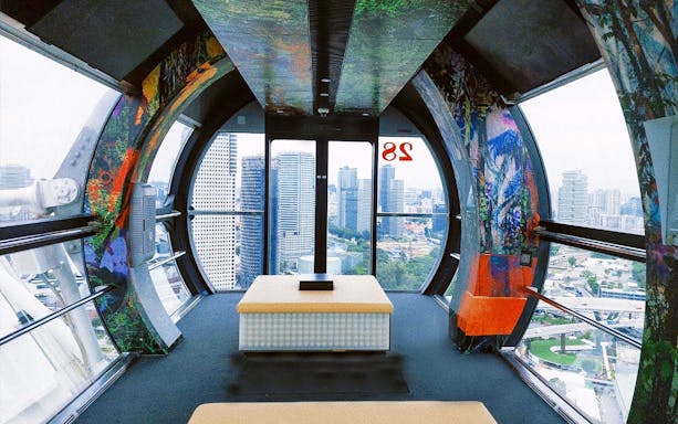 Interior view of Singapore Flyer capsule with city skyline in the background.