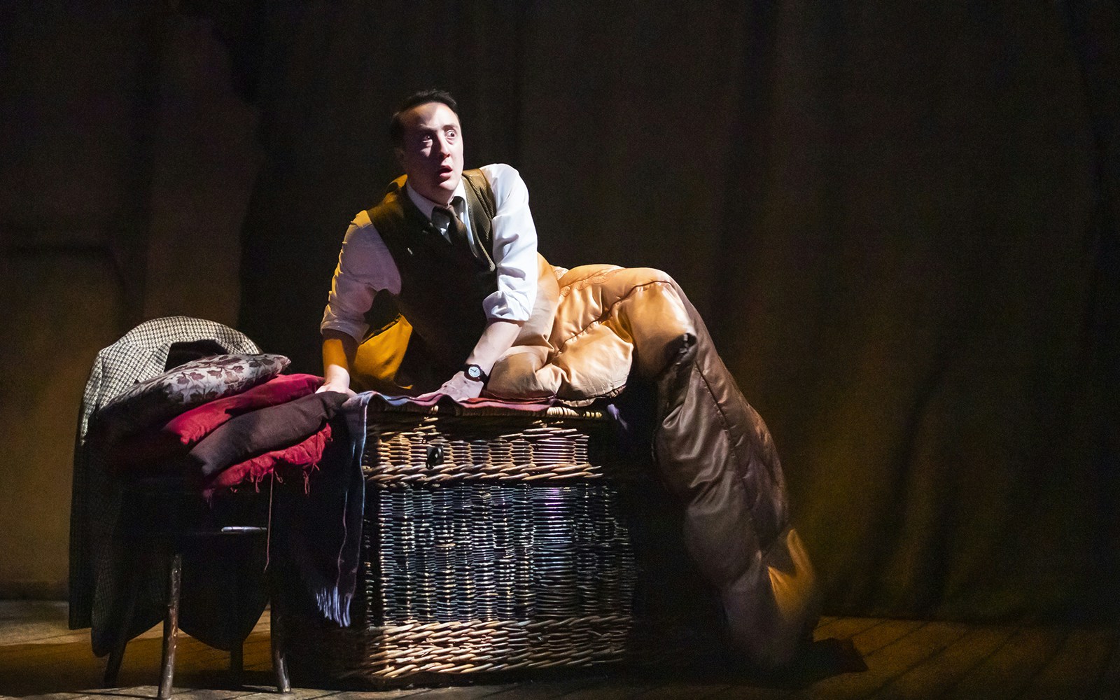 Actor on stage during "The Woman in Black" play, sitting on a wicker chest.