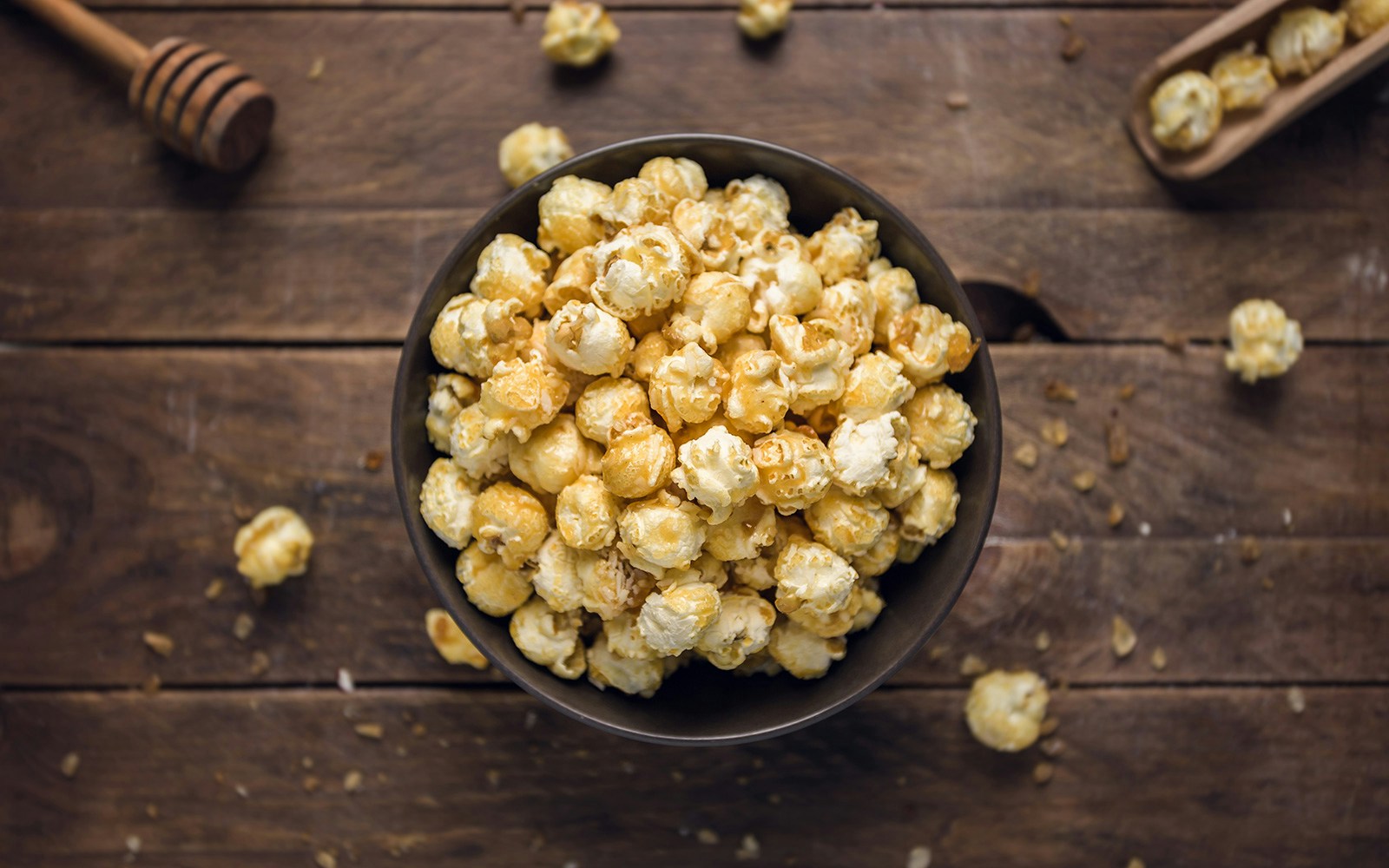 Popcorn in a bowl infused with honey on a wooden table.