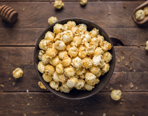 Popcorn infused with honey in a decorative bowl on a wooden table.