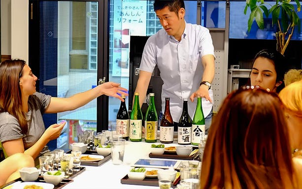 Kyoto sake tasting session with guide explaining different bottles to participants.