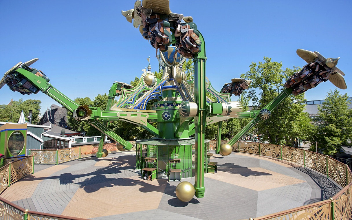 Aquila ride at Tivoli Gardens with passengers on rotating arms against a clear sky.