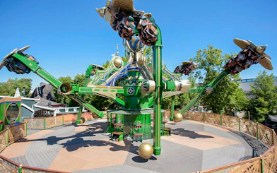 Aquila ride at Tivoli Gardens with passengers on rotating arms against a clear sky.