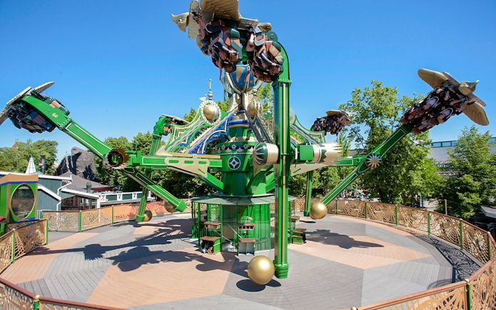 Aquila ride at Tivoli Gardens with passengers on rotating arms against a clear sky.