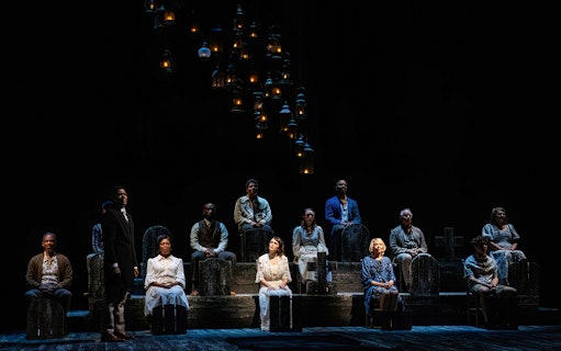 Cast of "Our Town" performing on stage with lanterns above.