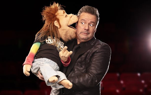 Ventriloquist with puppet on stage, part of "Terry Fator: One Man, a Hundred Voices, a Thousand Laughs!" show.