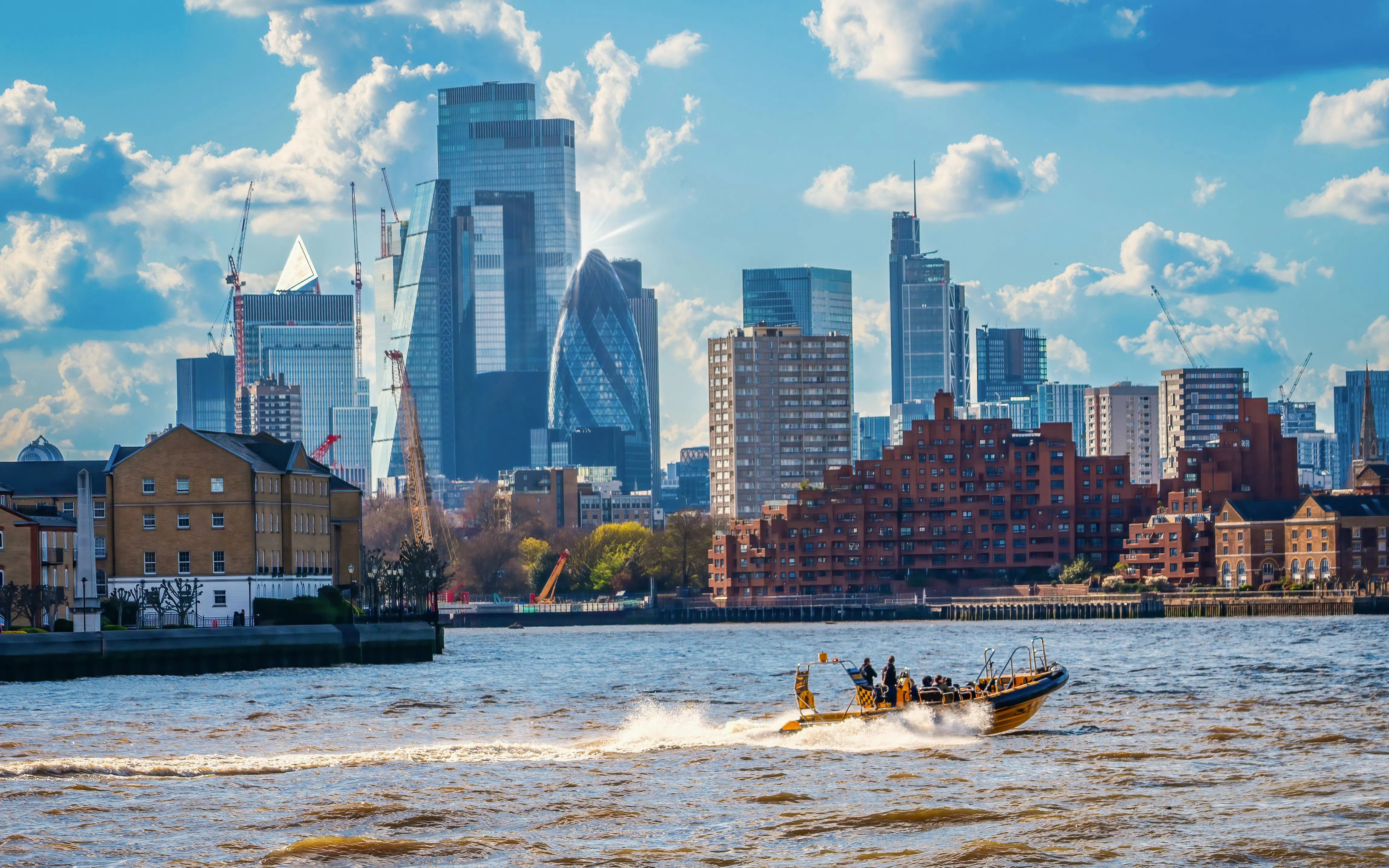 Speedboat on Thames River with London skyline in background.